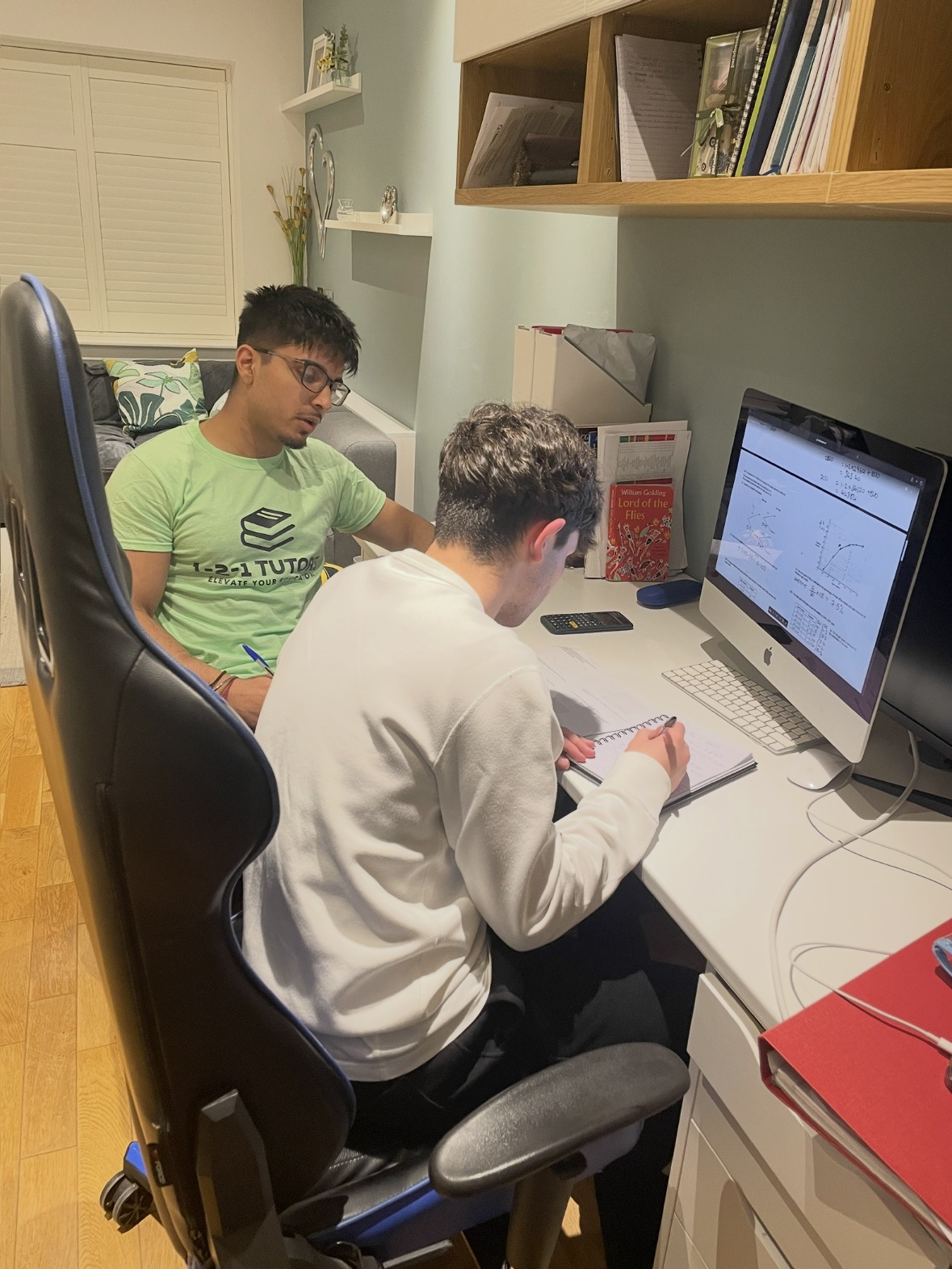 A 1-2-1 Tutors mentor sitting with a student at a desk